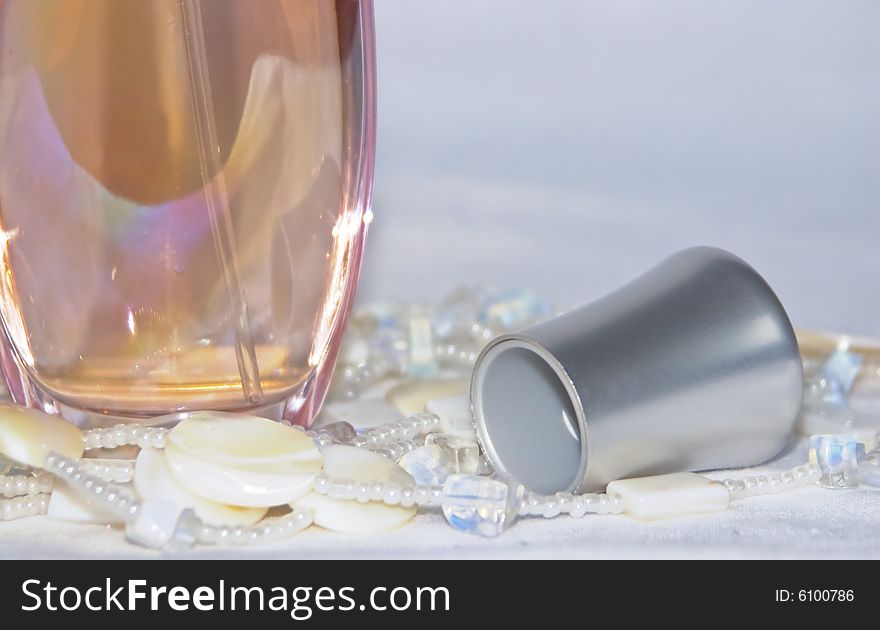 The image of a bottle with perfumery water and the scattered thread of a beads