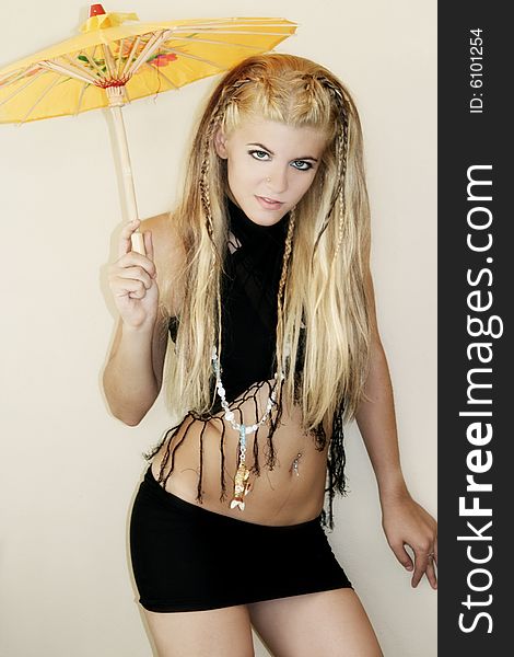 A beautiful young blonde woman in a fashion portrait holding a yellow chinese umbrella. A beautiful young blonde woman in a fashion portrait holding a yellow chinese umbrella