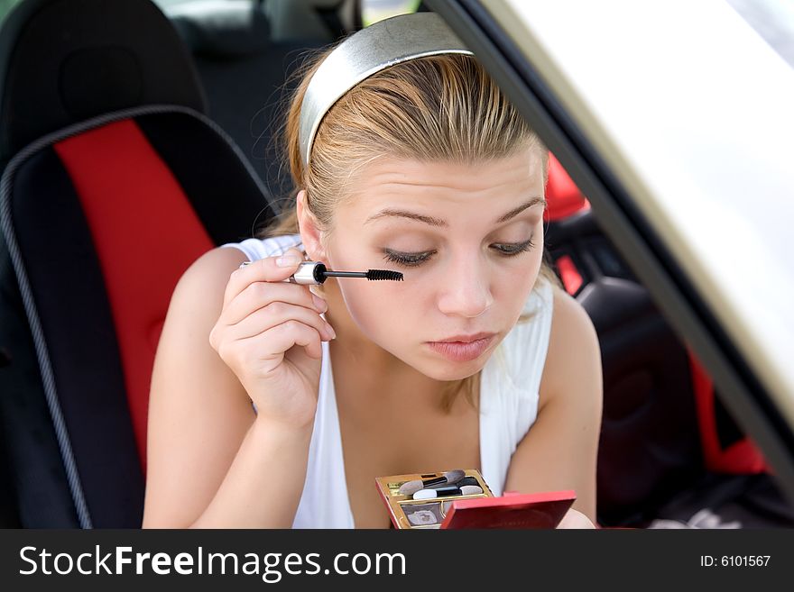 Beautiful girl make make-up in the car