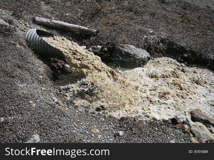 Dirty water running out of a large pipe. Dirty water running out of a large pipe.