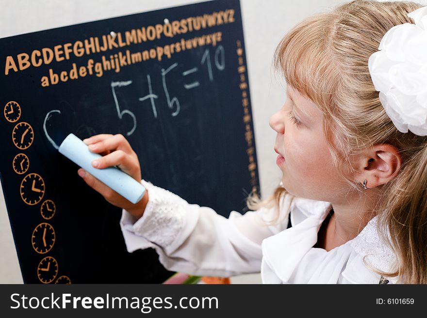 Little girl standing near blackboard. Writing on it. Little girl standing near blackboard. Writing on it.