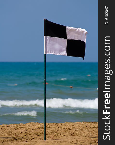 Quartered black and white flag on the beach, showing zoned off area