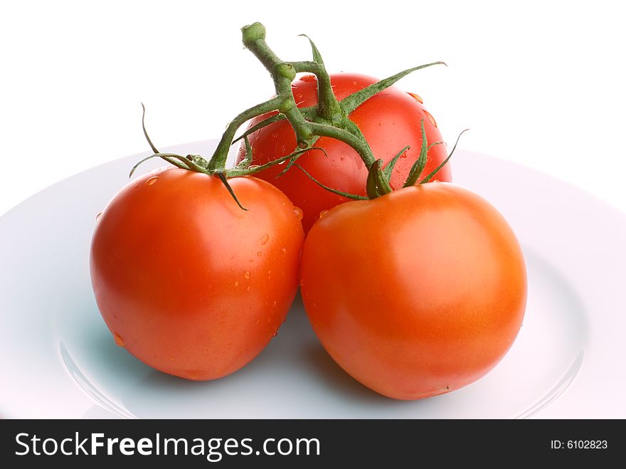 Three tomatoes on a plate isolated on white