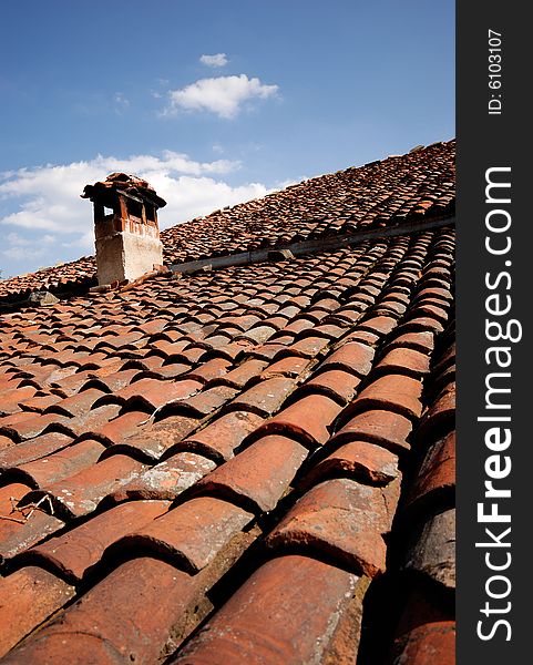 Red roof with chimney on blue sky