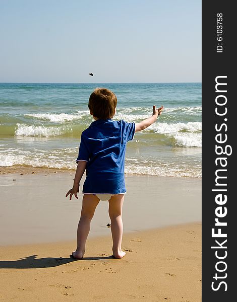 Little boy throwing stones into the sea. Little boy throwing stones into the sea