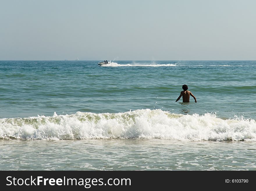 A young man walking into the summer sea. A young man walking into the summer sea