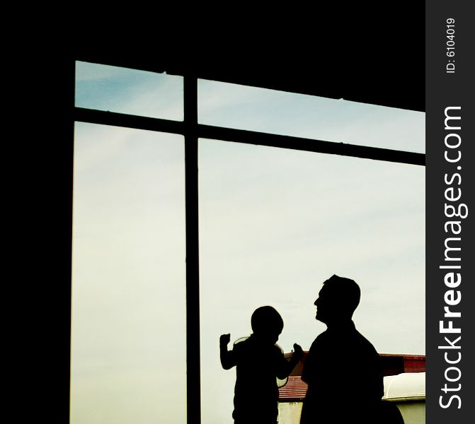 Silhouette of a father and his son at the window. Silhouette of a father and his son at the window