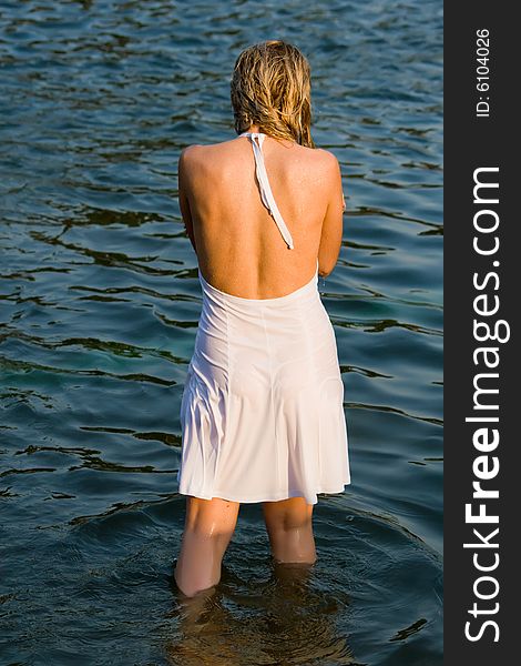 Girl in a white dress stands in water having turned a back. Girl in a white dress stands in water having turned a back
