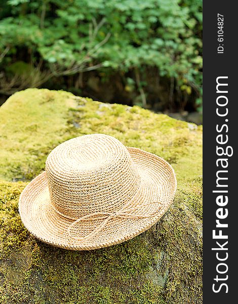 Straw raffia hat on rock in woods. Straw raffia hat on rock in woods