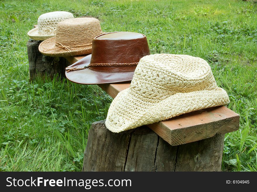 Straw and leather hats in a row on bench. Straw and leather hats in a row on bench