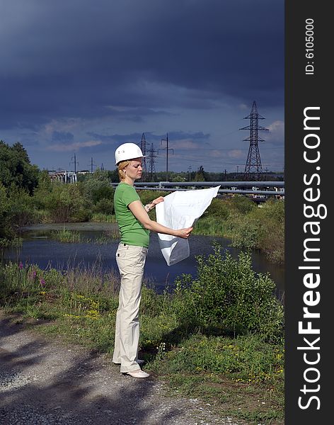 Woman engineer or architect with white safety hat, drawings and industrial pipelines on background. Woman engineer or architect with white safety hat, drawings and industrial pipelines on background
