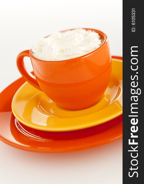 Orange coffee cup with yellow plate over white background