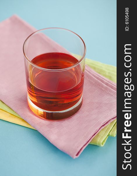 Glass of cranberry juice on pile of napkins