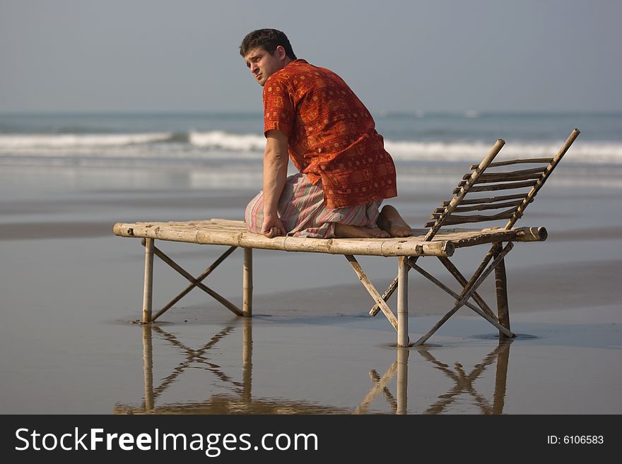 Man is siting on the trestle-bed on the beach. Man is siting on the trestle-bed on the beach