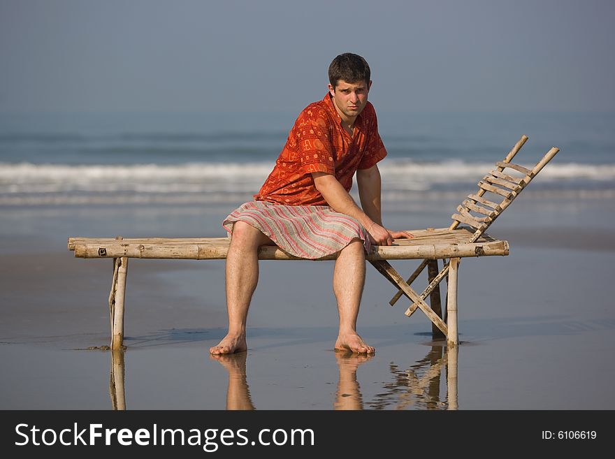 Man is siting on the trestle-bed on the beach. Man is siting on the trestle-bed on the beach