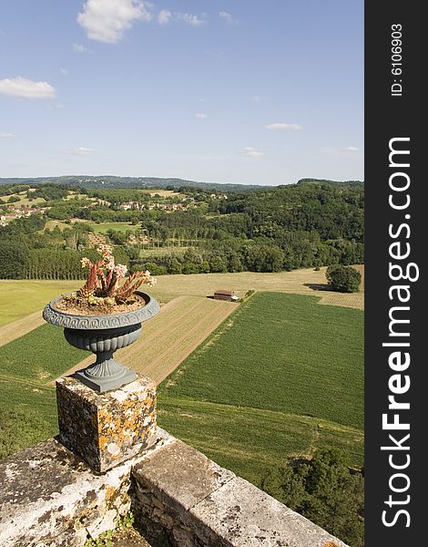 View over the fields of the Dordogne countryside with stone walls and flower pot in the foreground. View over the fields of the Dordogne countryside with stone walls and flower pot in the foreground