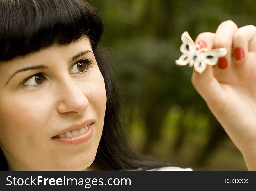 Outdoor portrait of pretty young brunette with brooch-butterfly
