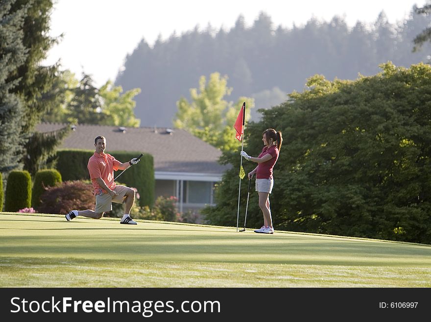 Couple playing golf by a golf cart. Horizontally framed shot. Couple playing golf by a golf cart. Horizontally framed shot.