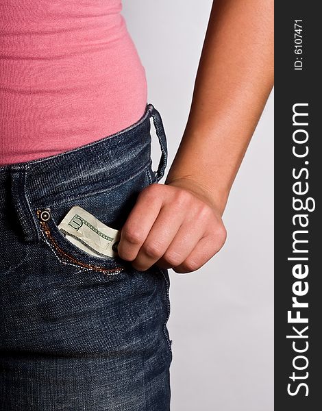 Teen girl with money to burn blue jeans and pink shirt stuffing money in front pocket. Teen girl with money to burn blue jeans and pink shirt stuffing money in front pocket