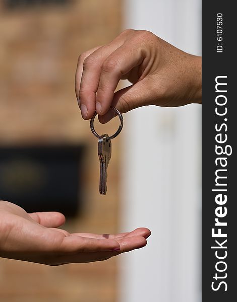 Woman handing another woman keys to a house. Woman handing another woman keys to a house