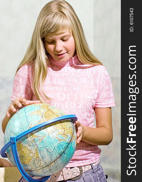 The schoolgirl studies the globe at a lesson at school. The schoolgirl studies the globe at a lesson at school