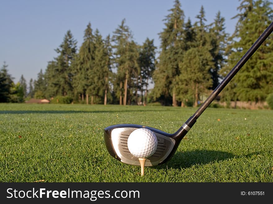 Head of golf club driver is aligned next to golf ball on tee. Horizontally framed photo. Head of golf club driver is aligned next to golf ball on tee. Horizontally framed photo.