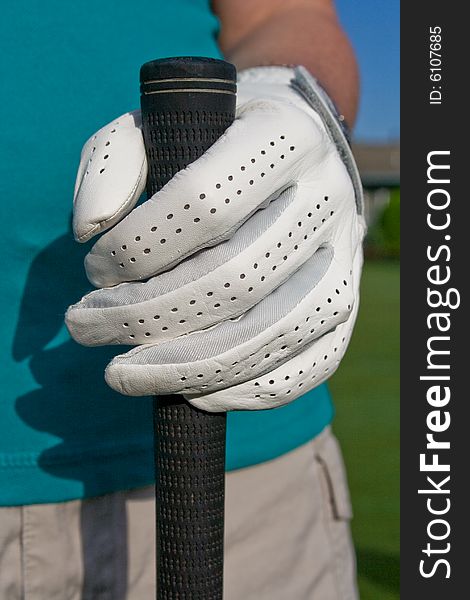 Golfer's gloved hand holds golf club. Vertically framed photo. Golfer's gloved hand holds golf club. Vertically framed photo.