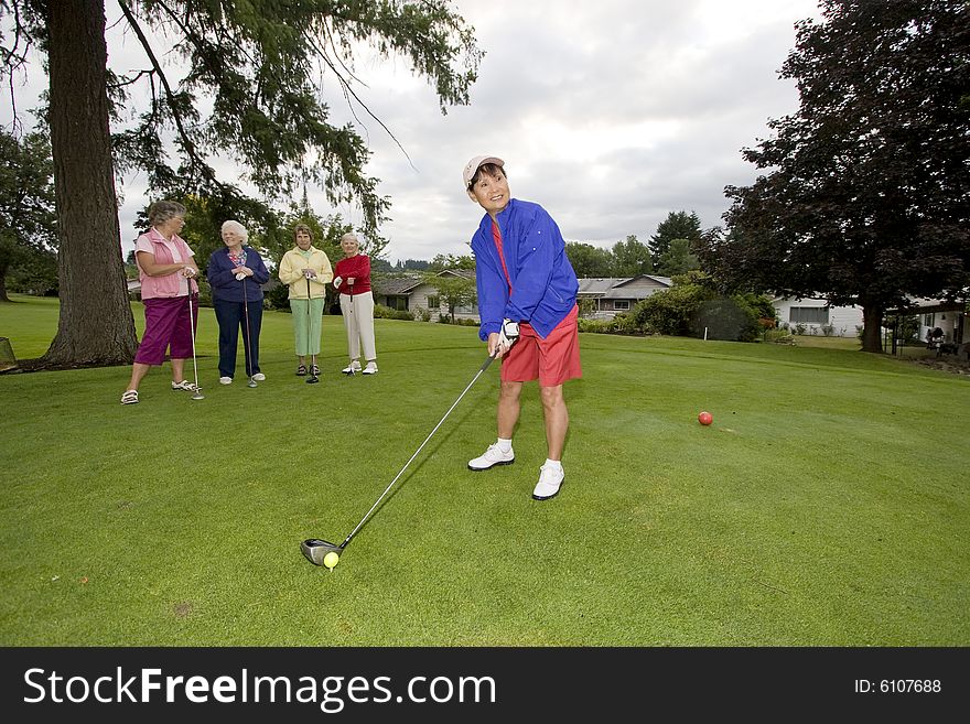 Five elderly women playing golf