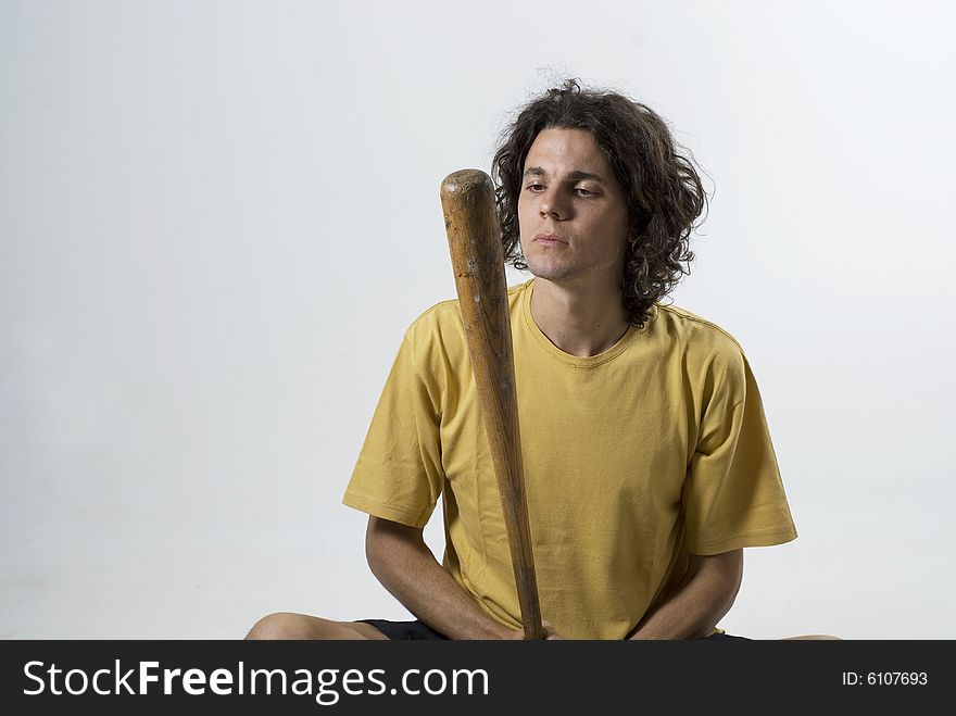 Man sitting cross legged looking at a baseball bat. Horizontally framed photograph. Man sitting cross legged looking at a baseball bat. Horizontally framed photograph