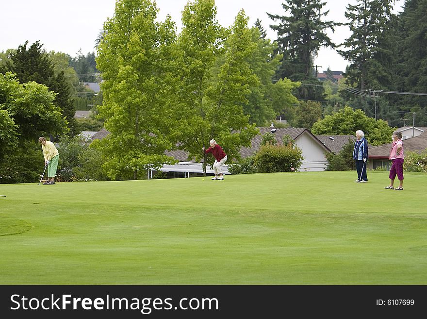 Group of four women playing golf. Horizontally framed photo.