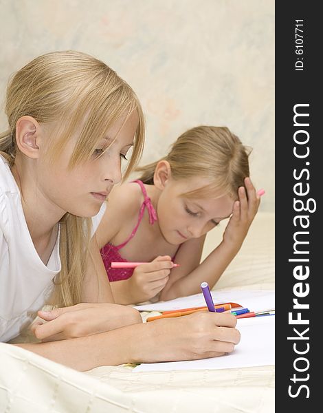 Two sisters do homework on sofa