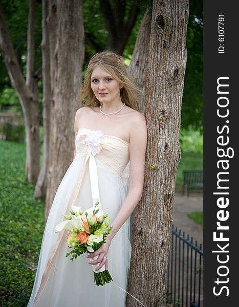 An image of a natural bride leaning against a tree