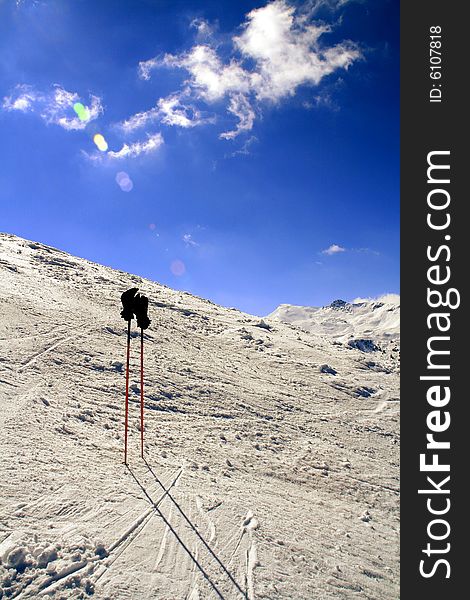 A pair of ski poles with gloves resting on them. A pair of ski poles with gloves resting on them