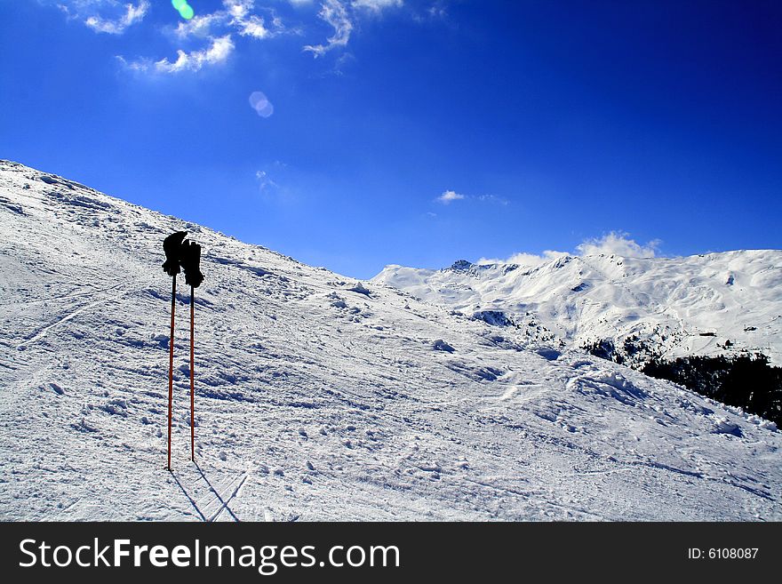 A pair of ski poles with gloves resting on them. A pair of ski poles with gloves resting on them