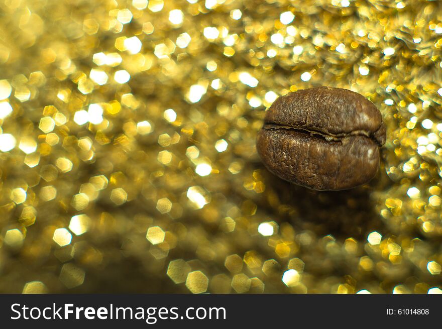 Coffee bean on golden color sparkling background texture