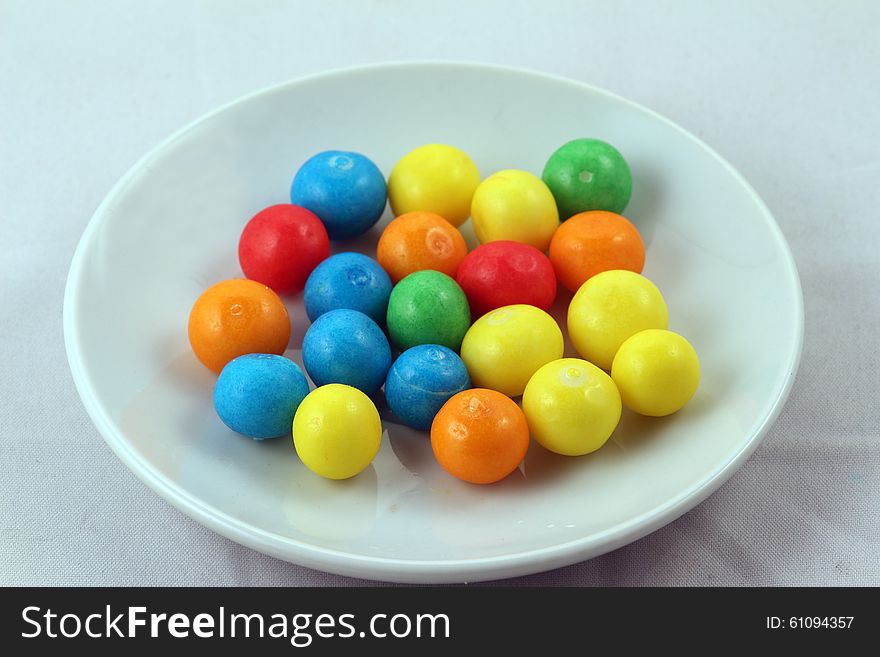 Sweets of different colours on white plate