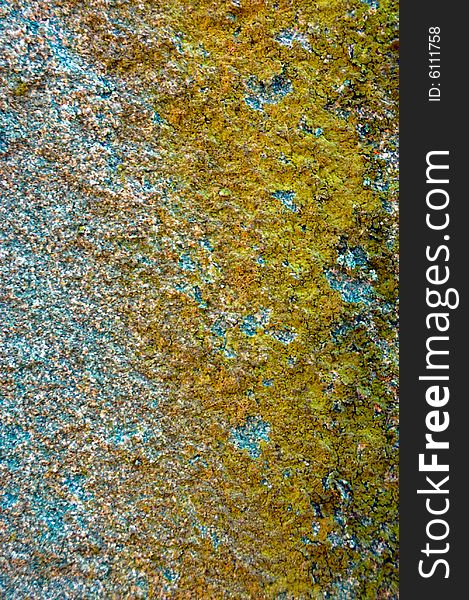 Colored (prevaling yellow and blue) rough stone surface with lichen