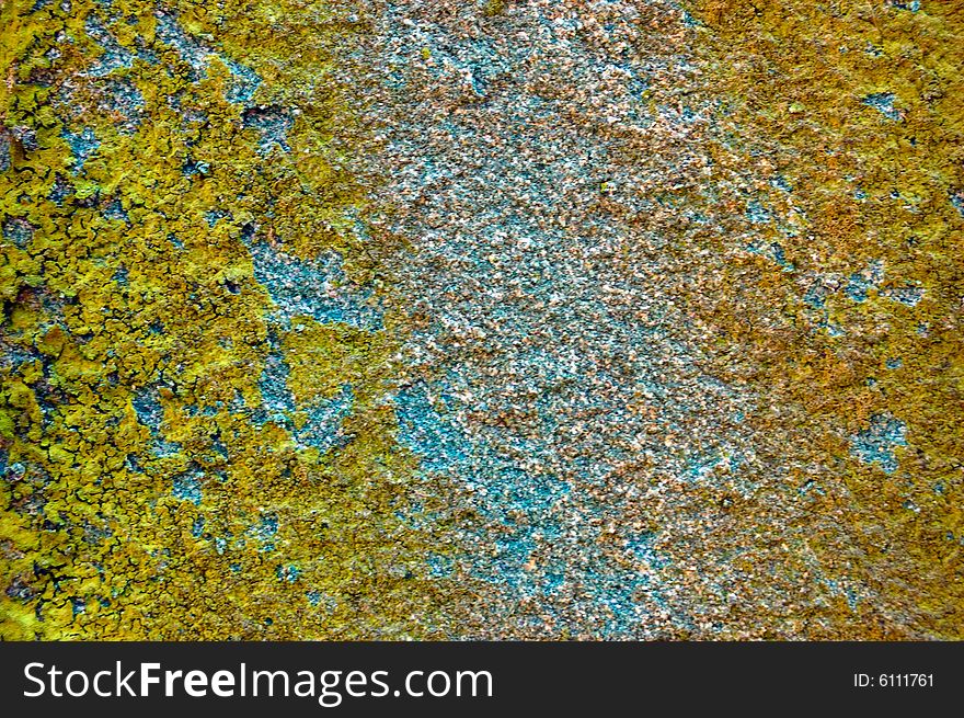 Colored (prevaling yellow and blue) rough stone surface with lichen