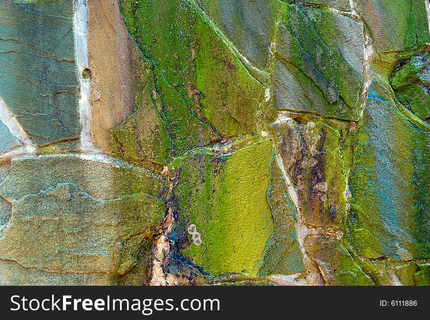 Colored (prevaling green) rough wall surface made of wild stones with lichen. Colored (prevaling green) rough wall surface made of wild stones with lichen