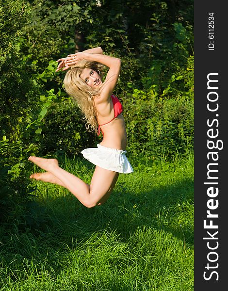 Beautiful girl jumps on a green grass in park