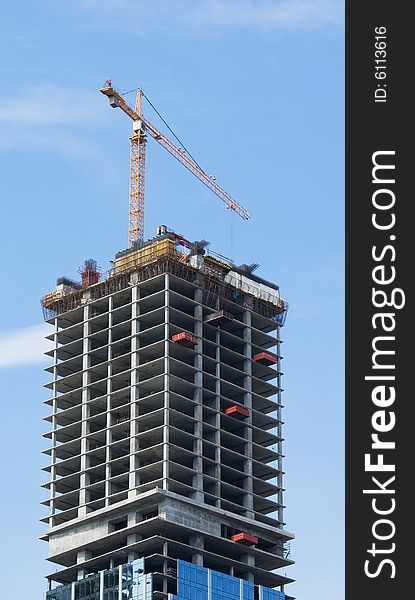 A skyscraper in construction phase with a crane over it. A skyscraper in construction phase with a crane over it