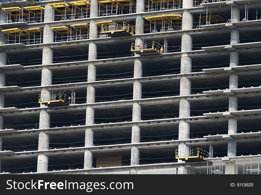 A skyscraper in construction phase with construction equipment on it. A skyscraper in construction phase with construction equipment on it