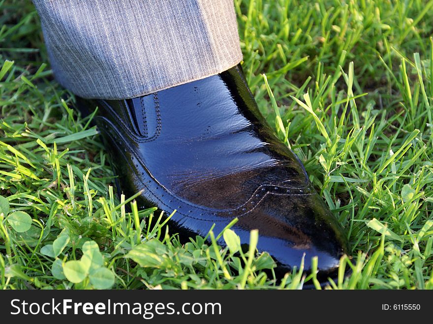 A man in suit and black shoes stands on the grass. A man in suit and black shoes stands on the grass