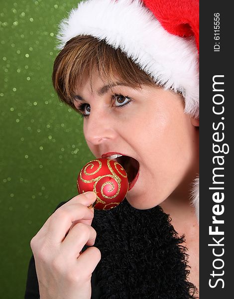 Adult female wearing a christmas hat, attempting to bite a decoration. Adult female wearing a christmas hat, attempting to bite a decoration