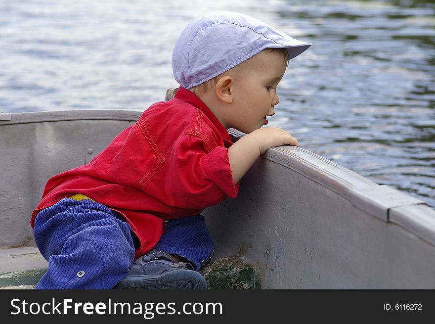 Small boy, two years, sits in the boat and looks at the water. Small boy, two years, sits in the boat and looks at the water