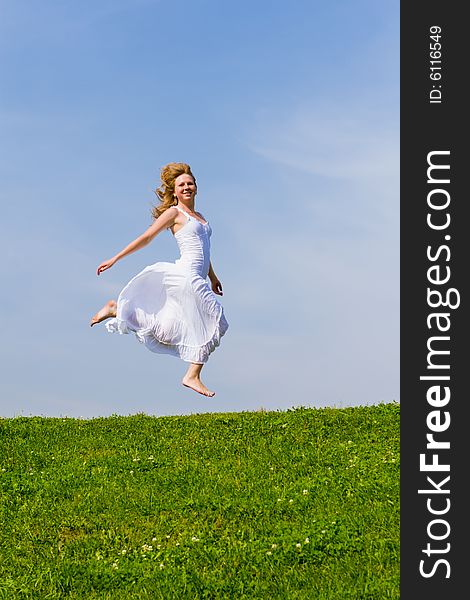 Girl runs on a grass on a background of the blue sky. Girl runs on a grass on a background of the blue sky