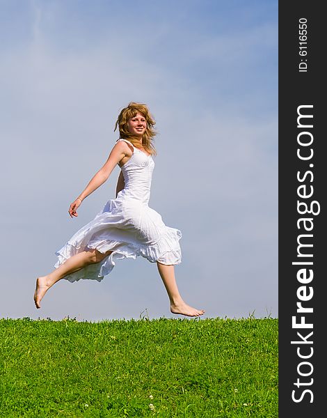 Girl runs on a grass on a background of the blue sky. Girl runs on a grass on a background of the blue sky
