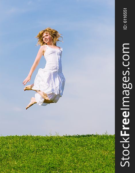 Girl jumps on a green grass on a background of the blue sky. Girl jumps on a green grass on a background of the blue sky