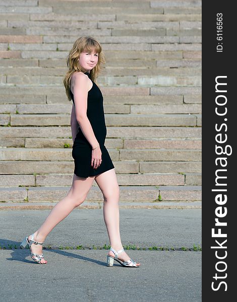 Girl in a black dress goes along steps