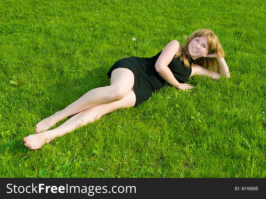 Girl in a black dress lays on a green grass. Girl in a black dress lays on a green grass